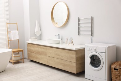 Stylish bathroom interior with heated towel rail and washing machine