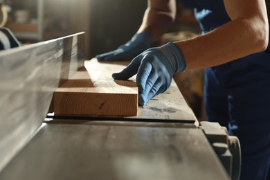 Photo of Professional carpenter working with wood in shop, closeup