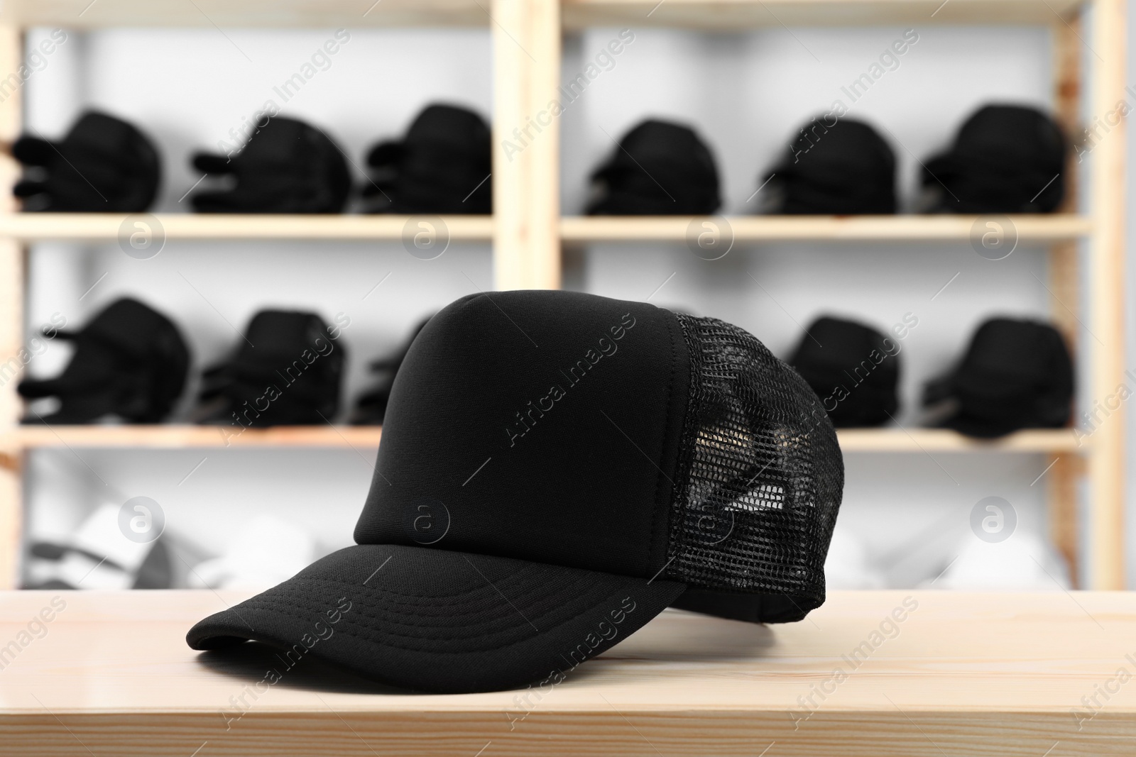 Photo of Blank black cap on wooden table in store. Mock up for design