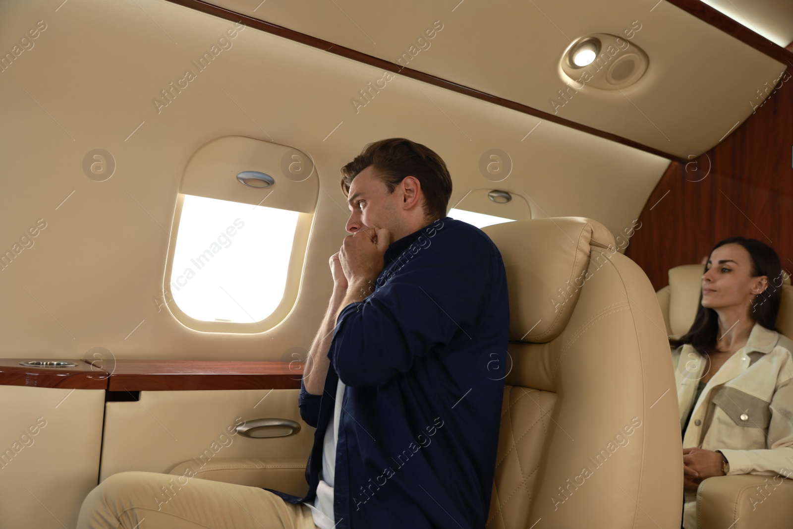 Photo of Nervous young man suffering from aviophobia in airplane
