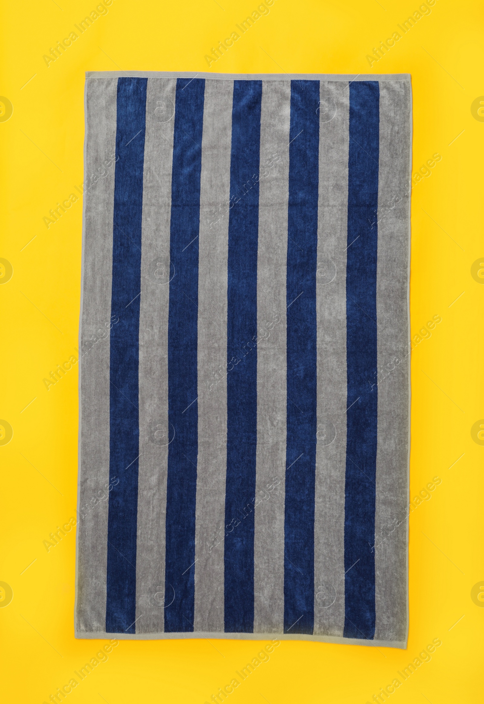 Photo of Striped beach towel on yellow background, top view