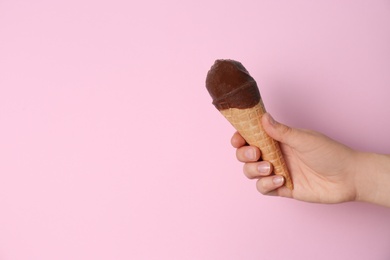 Photo of Woman holding ice cream in waffle cone against color background, space for text