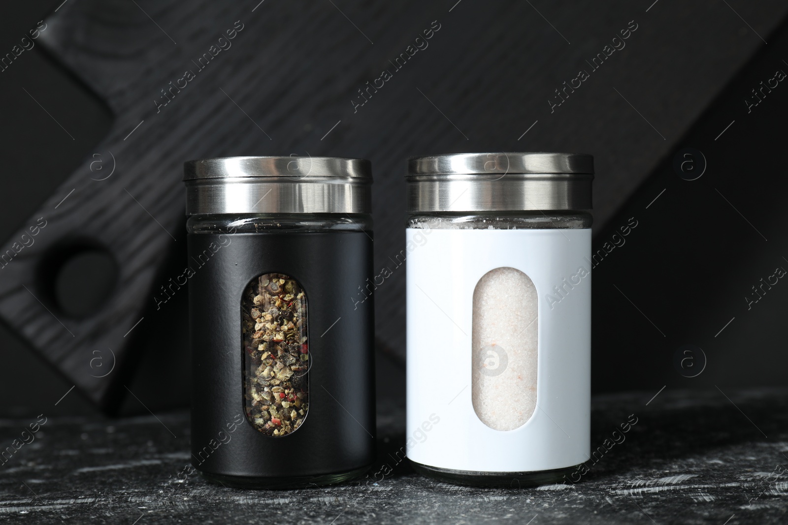 Photo of Salt and pepper shakers on dark table