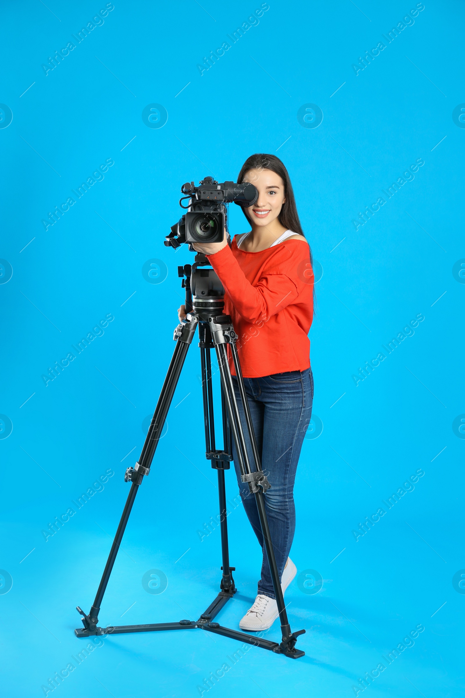 Photo of Operator with professional video camera on blue background