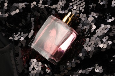Photo of Luxury perfume in bottle on fabric with shiny sequins