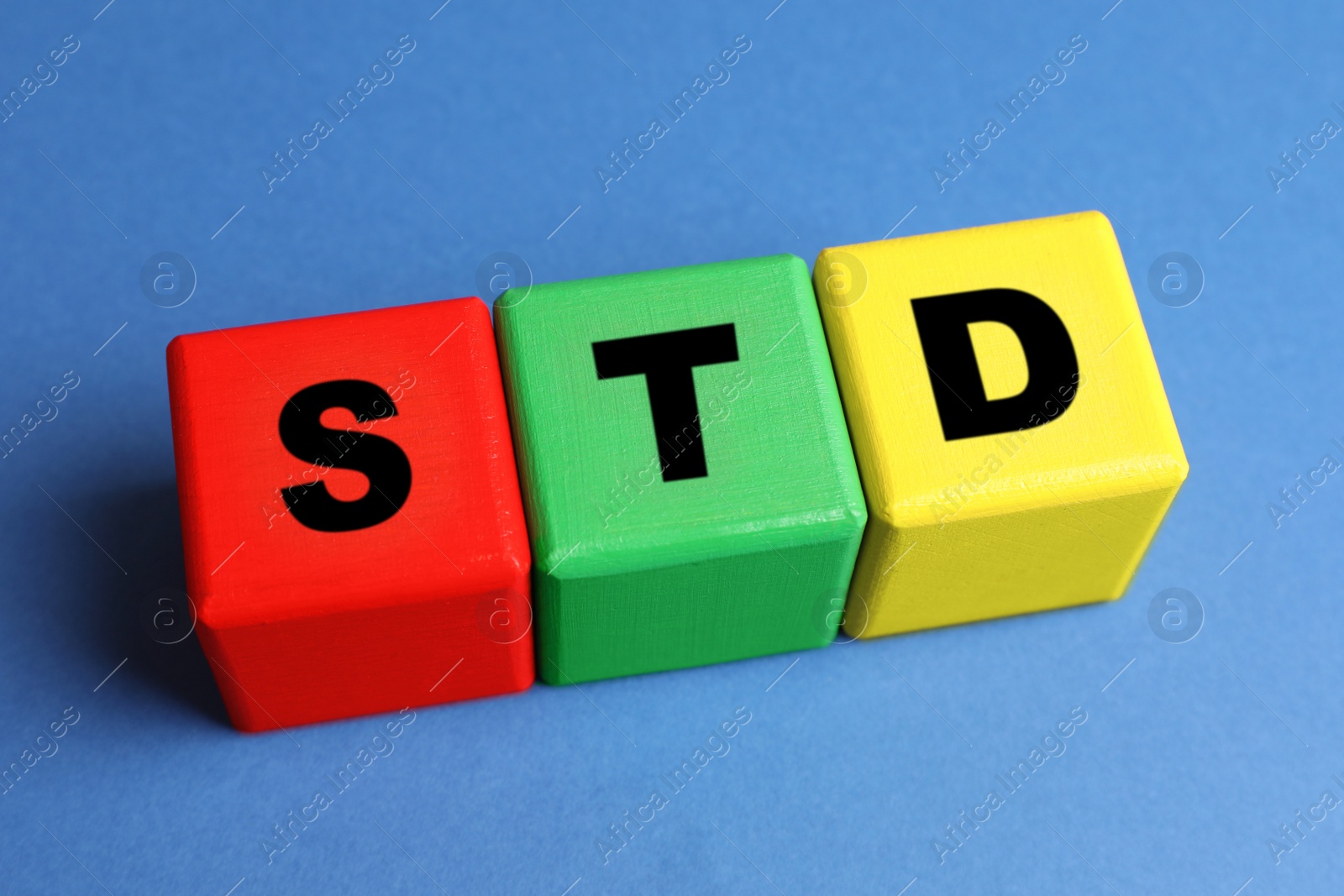 Photo of Abbreviation STD made with cubes on blue background