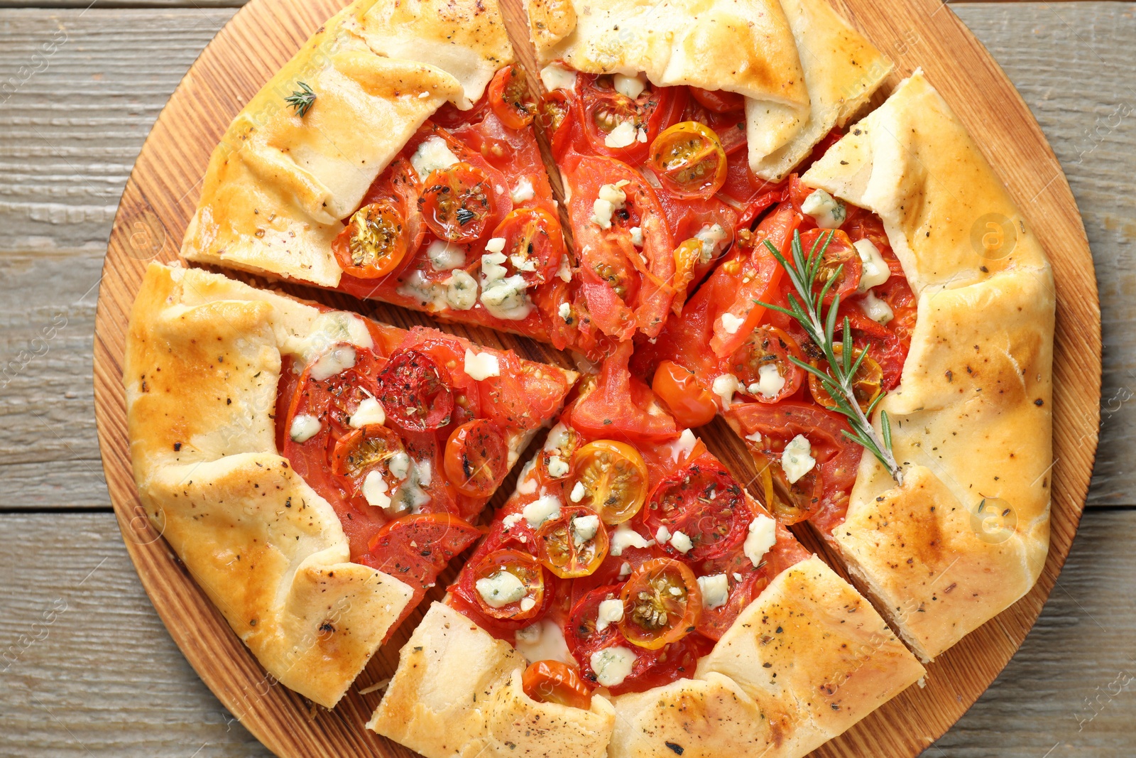 Photo of Tasty galette with tomato, rosemary and cheese (Caprese galette) on wooden table, top view