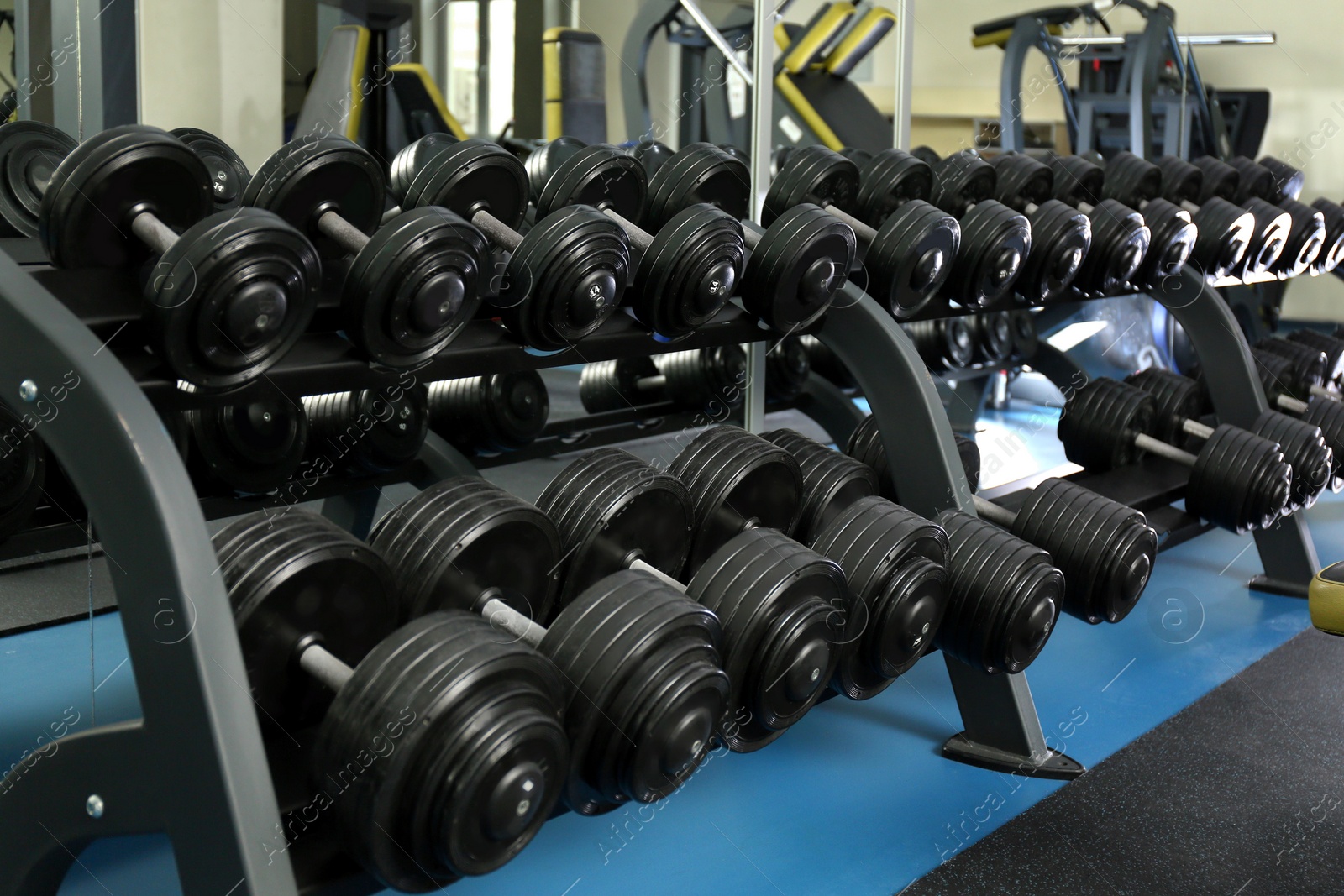 Photo of Dumbbells on rack in gym. Modern sport equipment