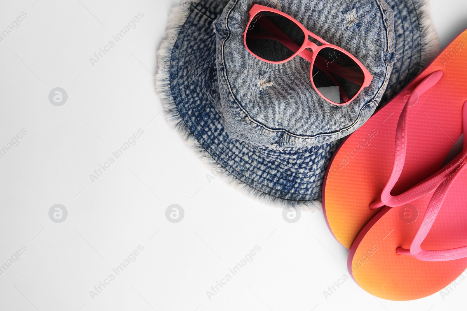 Photo of Sunglasses, hat and bright flip flops on white background, flat lay with space for text. Beach accessories