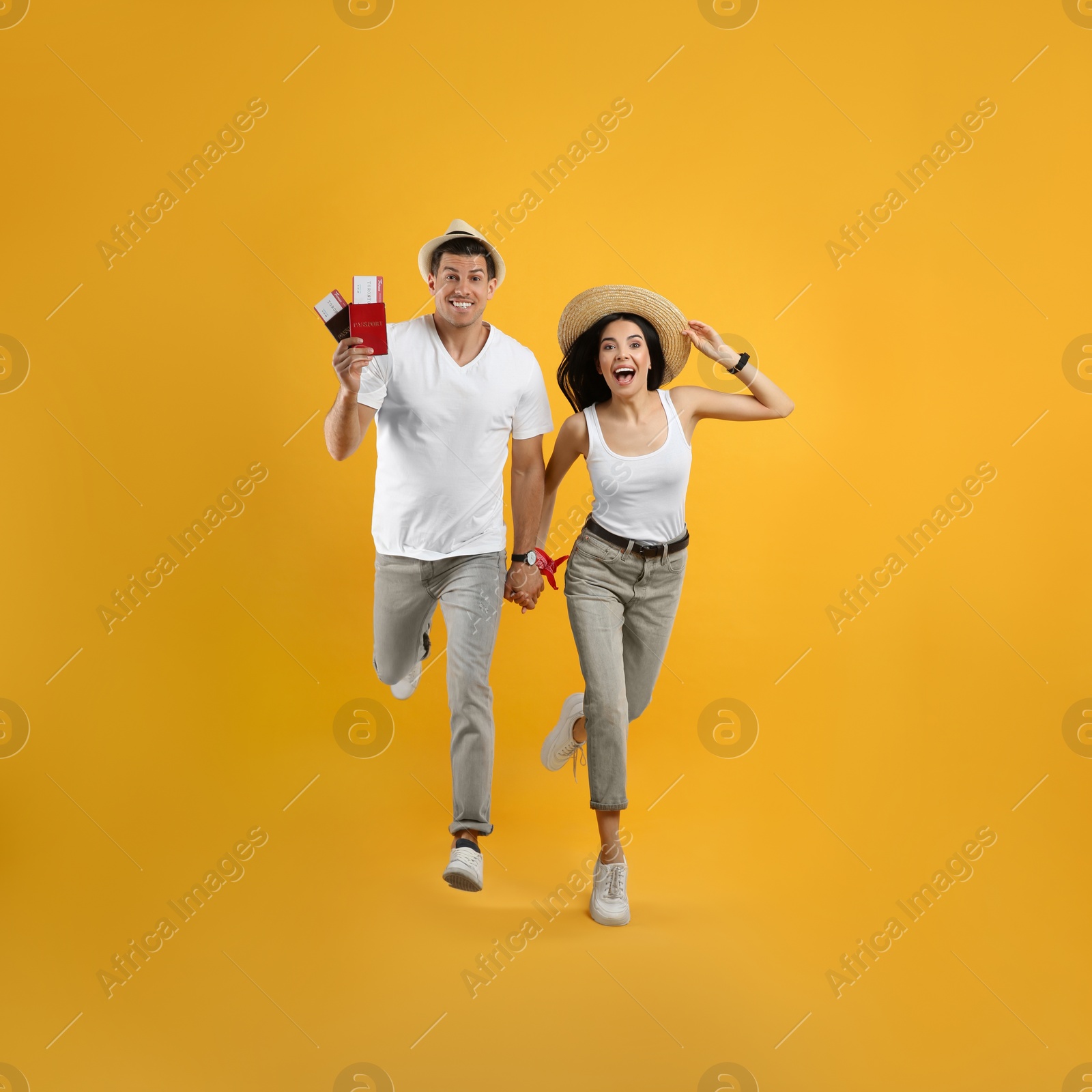 Photo of Couple of tourists with tickets and passports running on yellow background