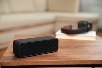 Photo of One black portable bluetooth speaker on wooden table indoors, space for text. Audio equipment