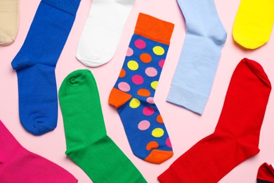 Photo of Many different colorful socks on light pink background, flat lay
