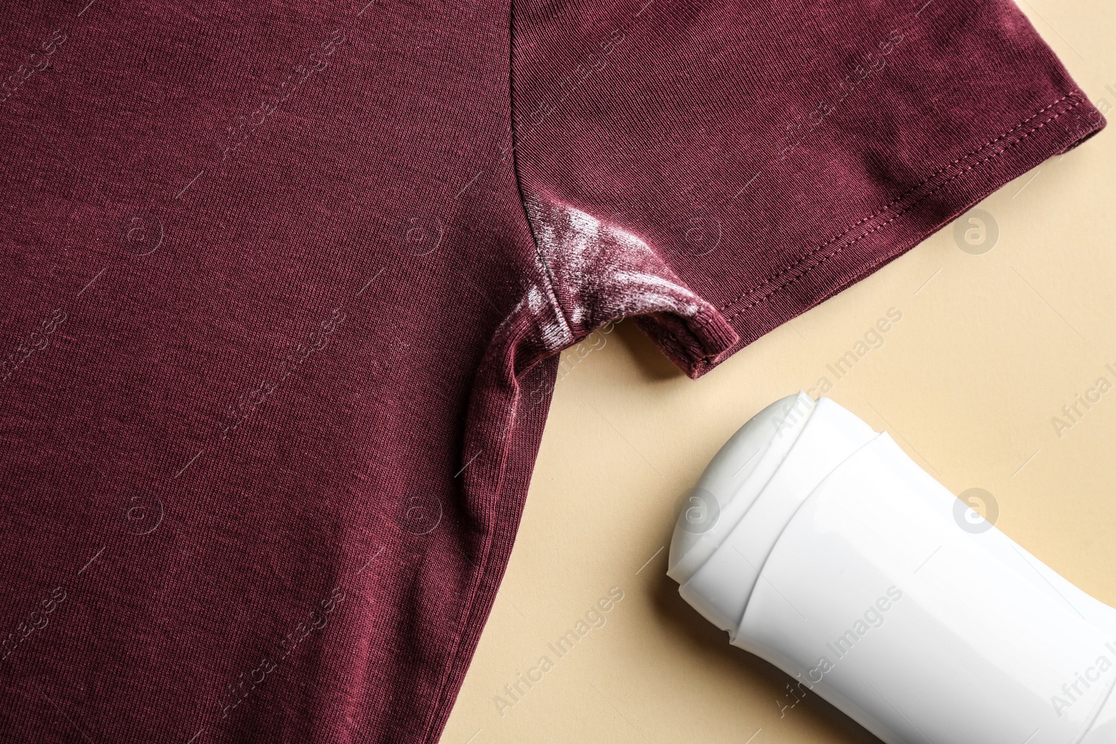 Photo of Clothes with stain and deodorant on beige background, closeup