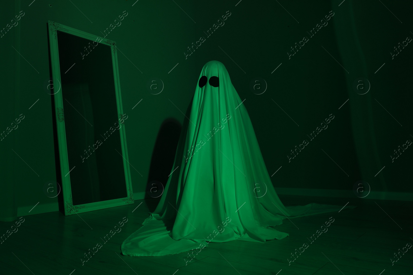 Photo of Creepy ghost. Woman covered with sheet in green light