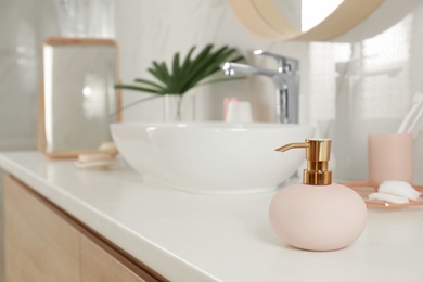 Photo of Elegant pink dispenser on light countertop in bathroom interior