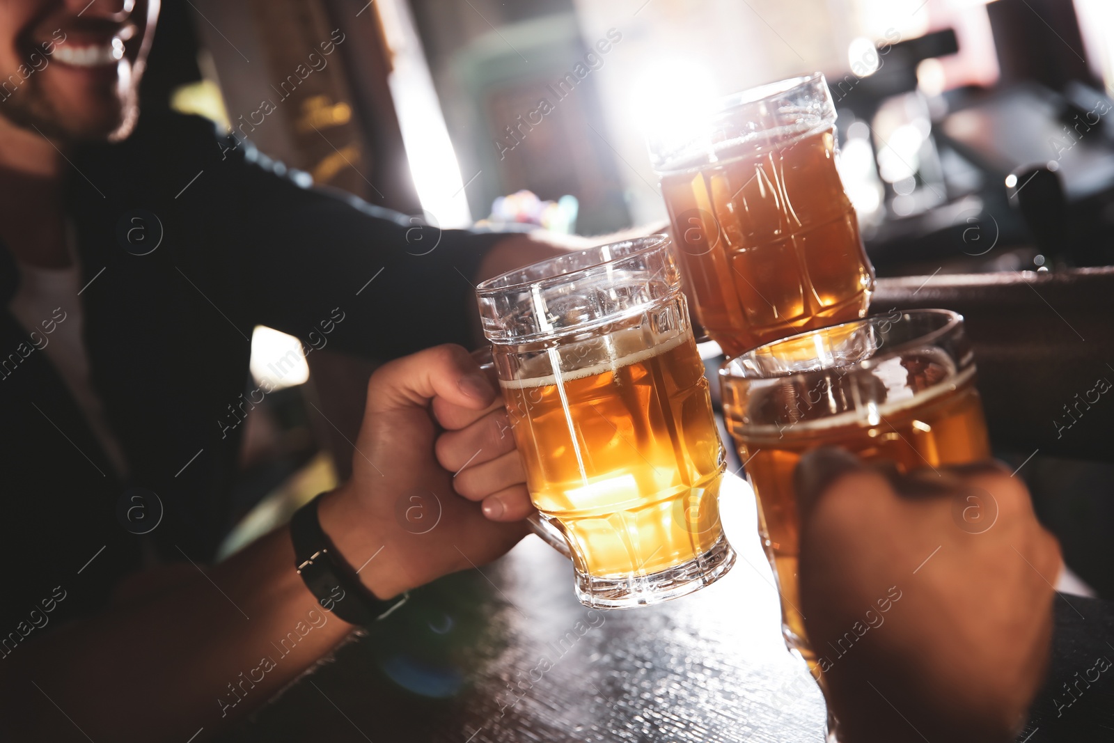 Photo of Friends clinking glasses with beer in pub, closeup