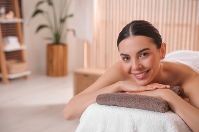 Photo of Young woman resting on massage couch in spa salon, space for text