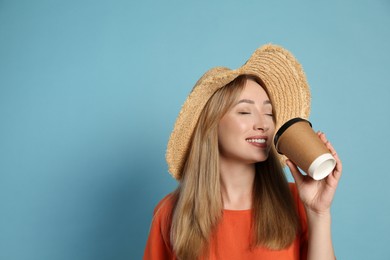 Photo of Beautiful young woman with straw hat drinking coffee from paper cup on light blue background, space for text. Stylish headdress