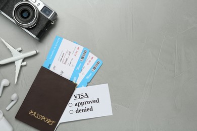 Flat lay composition with passport, toy plane and camera on grey background, space for text. Visa receiving
