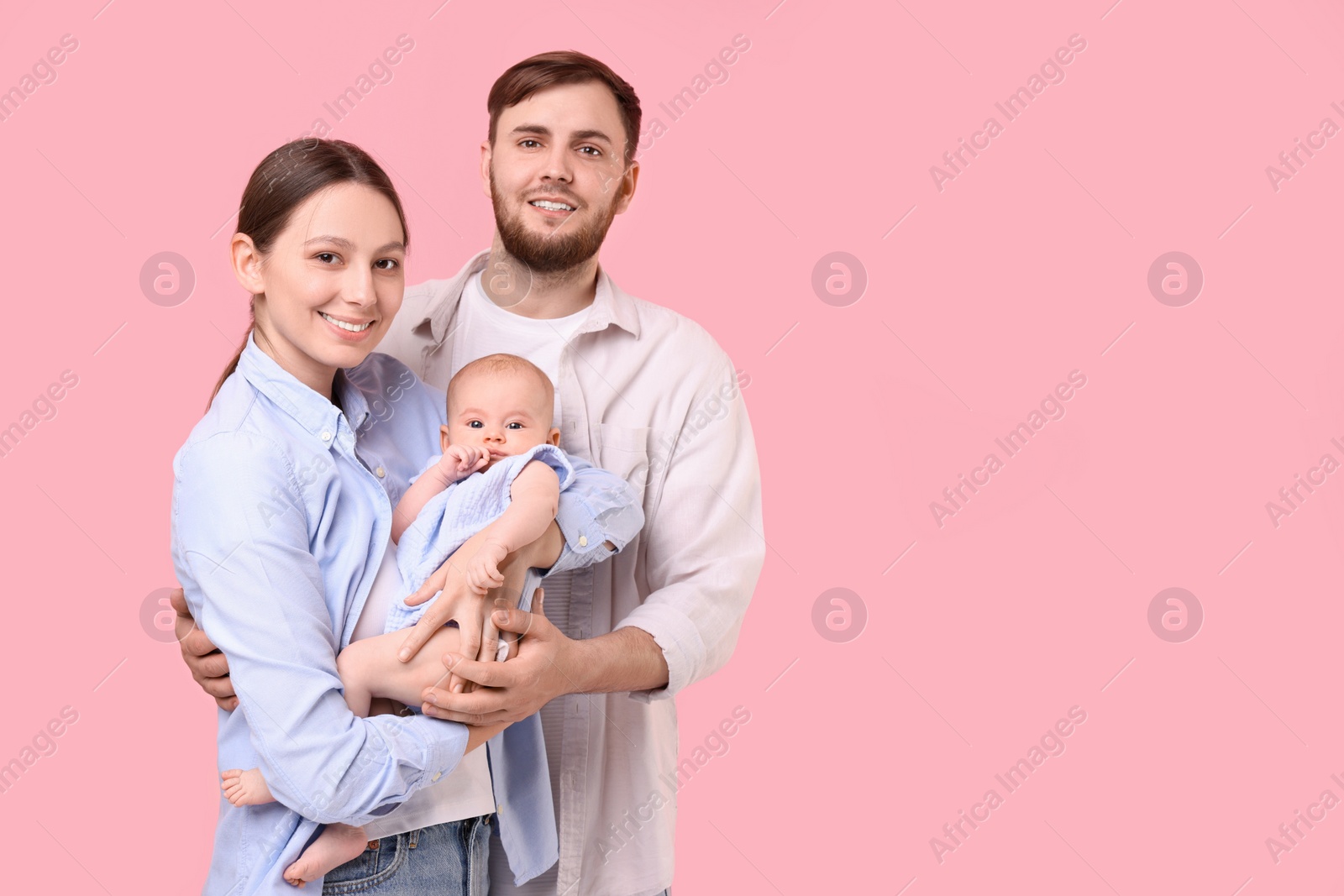 Photo of Happy family. Parents with their cute baby on pink background, space for text