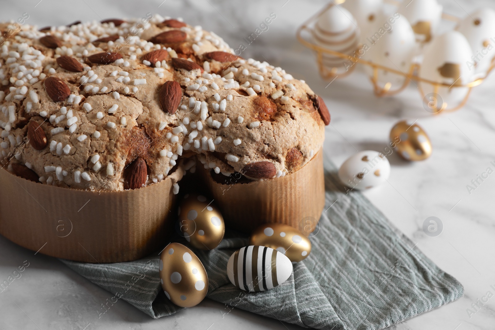 Photo of Delicious Italian Easter dove cake (Colomba di Pasqua) and decorated eggs on white marble table, closeup