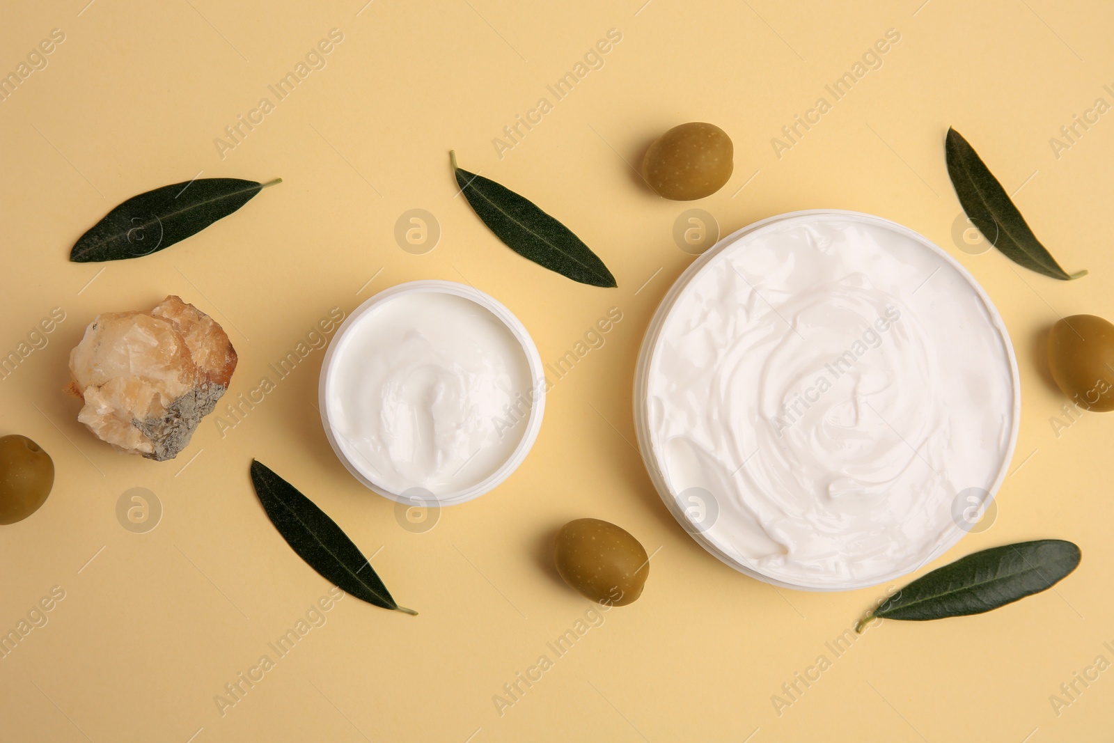 Photo of Natural cosmetic. Different olive creams, mineral and ingredient on beige background, flat lay