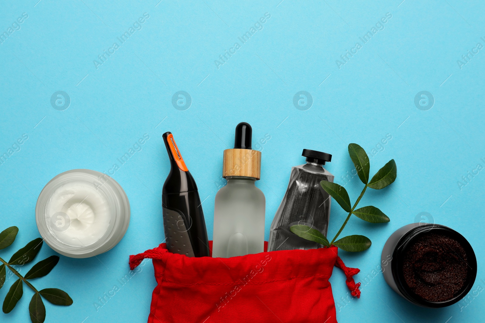 Photo of Preparation for spa. Red toiletry bag with different cosmetic products and twigs on light blue background, flat lay. Space for text