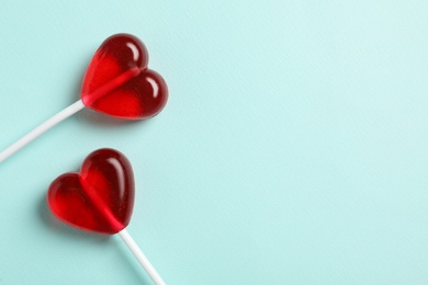 Photo of Sweet heart shaped lollipops on light blue background, flat lay with space for text. Valentine's day celebration