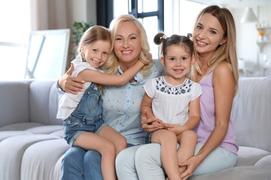 Photo of Young woman with mature mother and little daughters in living room