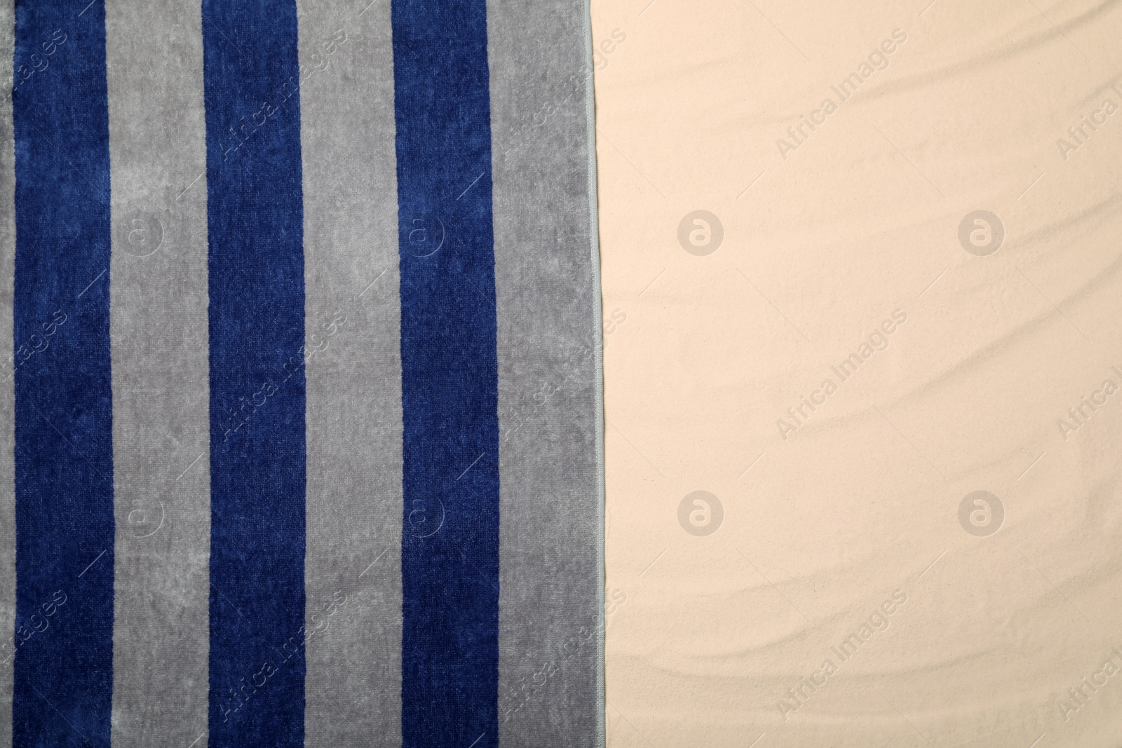 Photo of Striped beach towel on sand, top view. Space for text