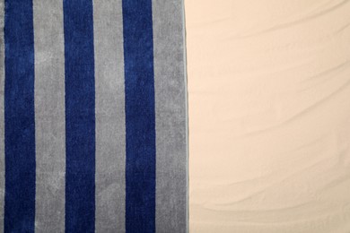 Photo of Striped beach towel on sand, top view. Space for text