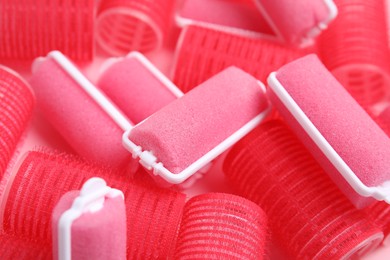 Photo of Different hair curlers on pink background, closeup. Styling tool