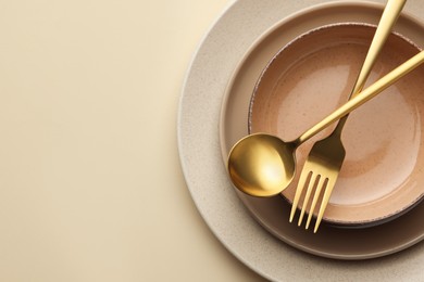Photo of Stylish empty dishware and cutlery on beige background, top view. Space for text