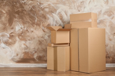 Pile of cardboard boxes near brown wall indoors. Space for text