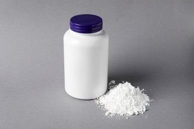 Photo of Bottle and calcium carbonate powder on grey background