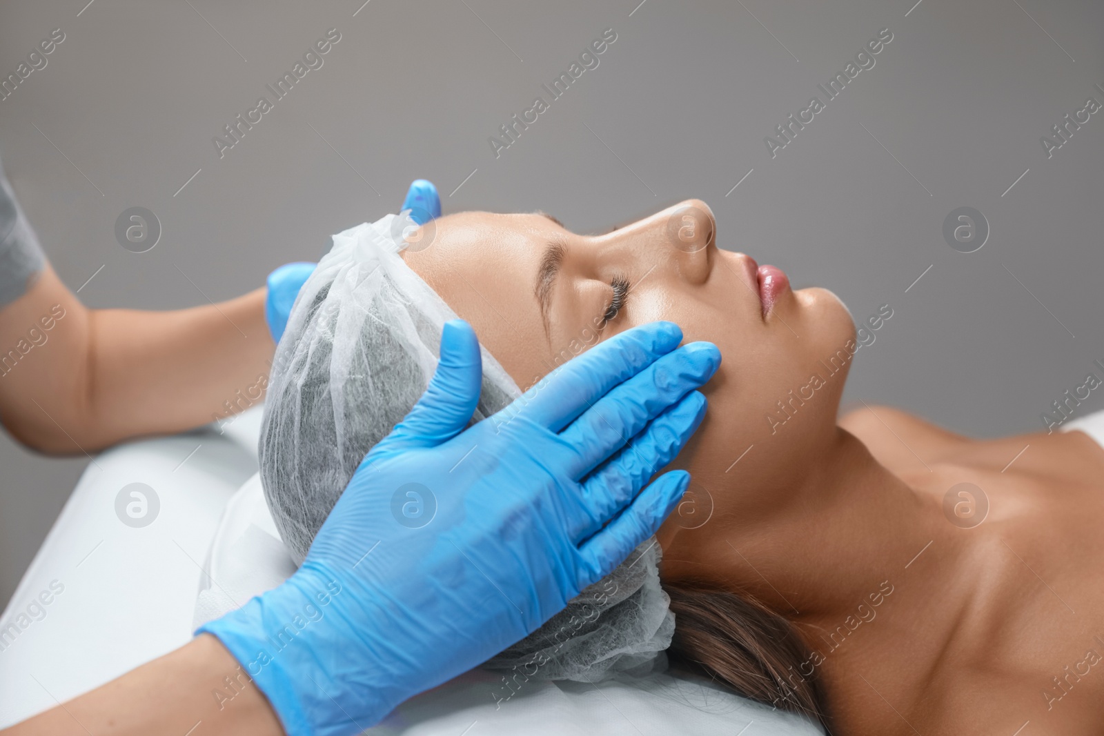 Photo of Young woman receiving facial massage in salon