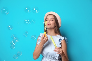 Photo of Young woman blowing soap bubbles on color background