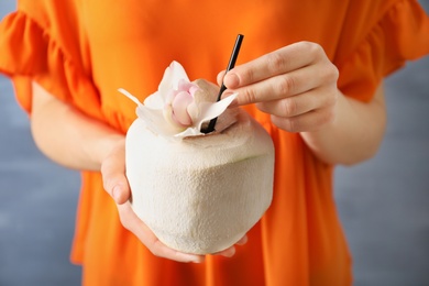 Photo of Woman with fresh coconut drink in nut on color background, closeup