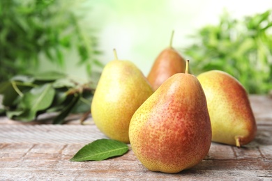 Heap of ripe juicy pears on brown wooden table against blurred background. Space for text