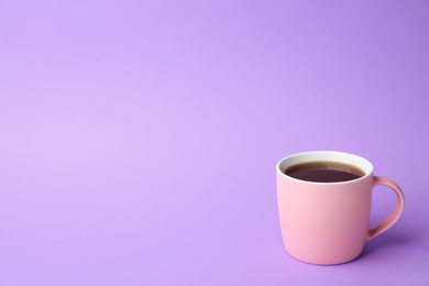 Pink ceramic cup with hot aromatic coffee on color background