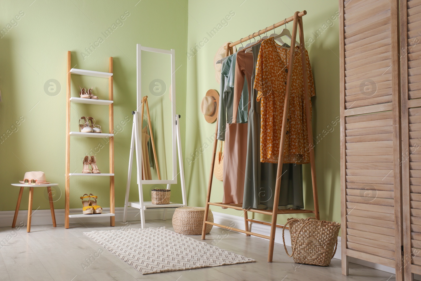 Photo of Modern dressing room interior with clothing rack and mirror near light green wall
