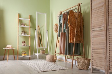 Modern dressing room interior with clothing rack and mirror near light green wall