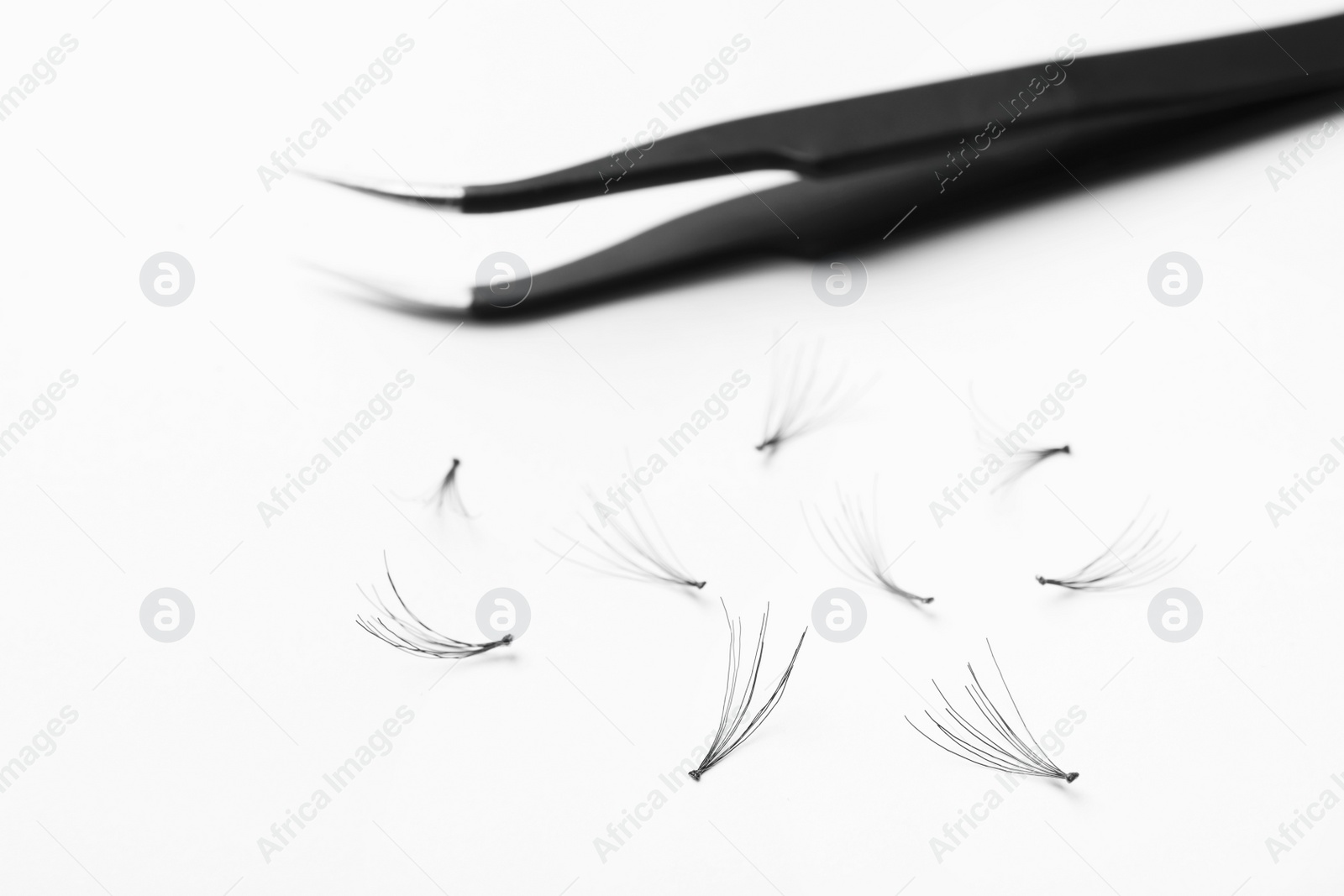 Photo of False eyelashes and tweezers on white background, closeup