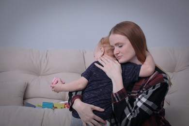 Young single mother hugging her child in living room