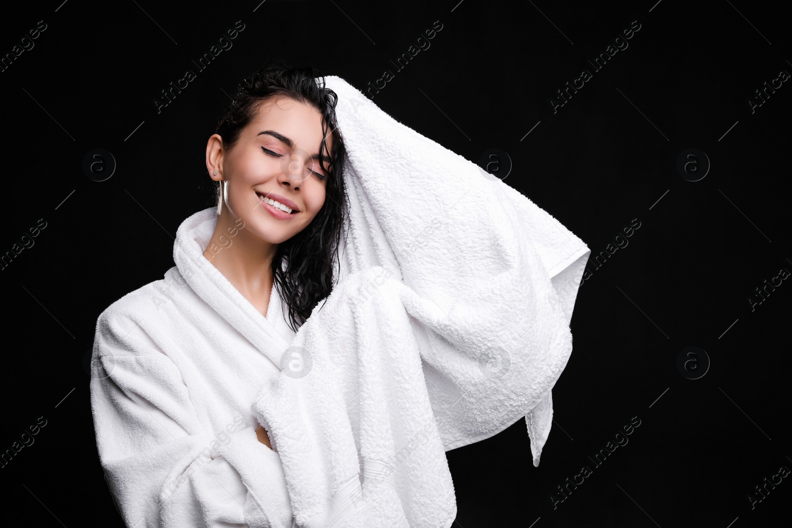 Photo of Pretty woman drying hair with towel after washing on black background