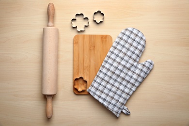 Photo of Flat lay composition with oven glove and kitchenware on wooden table
