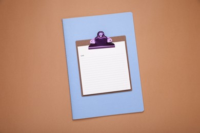 Photo of Clipboard with to do notes and planner on brown background, top view. Space for text