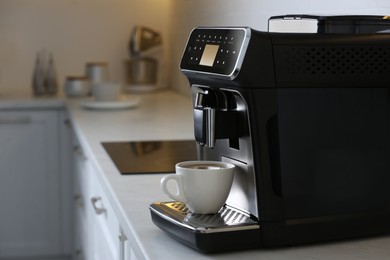 Photo of Modern electric espresso machine with cup of coffee on white marble countertop in kitchen