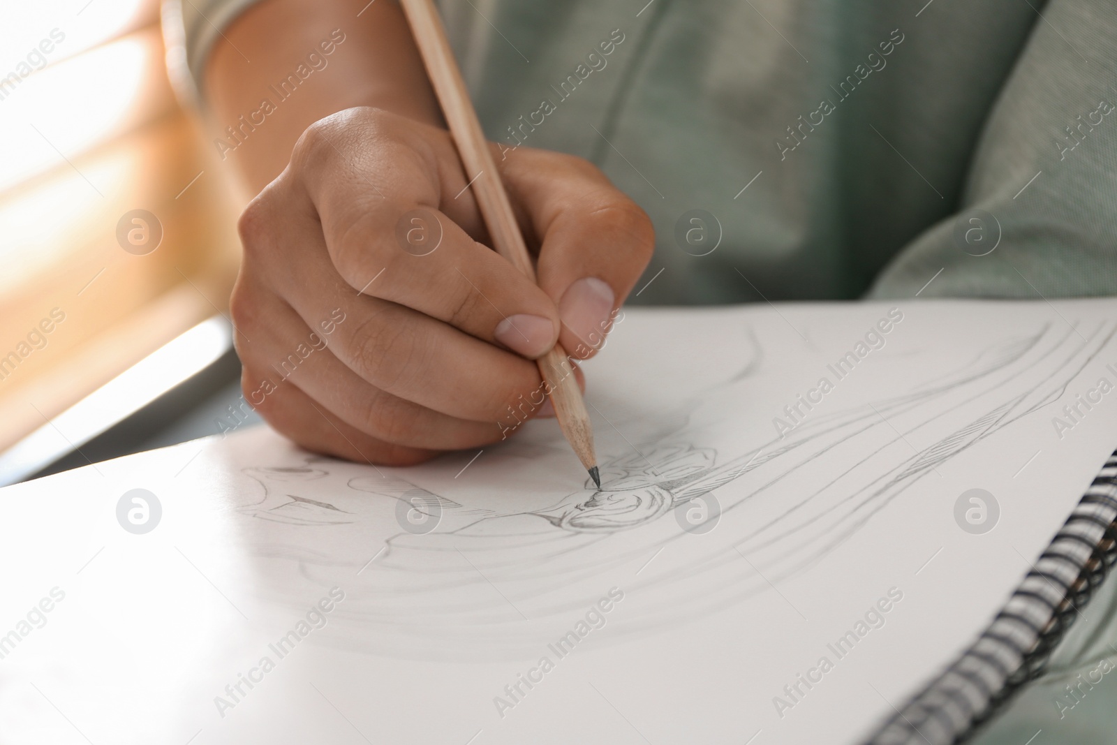 Photo of Man drawing portrait with pencil in notepad indoors, closeup