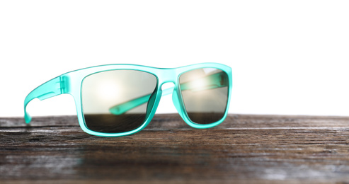 Photo of Stylish sunglasses on wooden table against white background